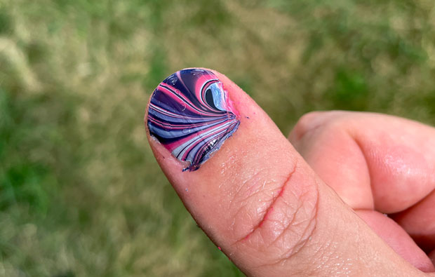 a thumb with a coluorful parttern painted on its nail