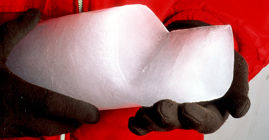 Ice core being held by gloved hands.