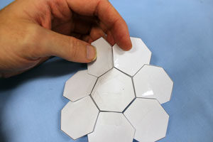a flower shape of heptagons. someone is taping two ajacent heptagons together.