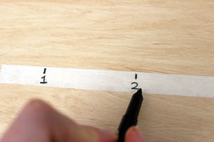 Someone is writing numbers on a strip of masking tape.
