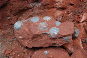 A big red rock with lots of smaller gray lumps in it.