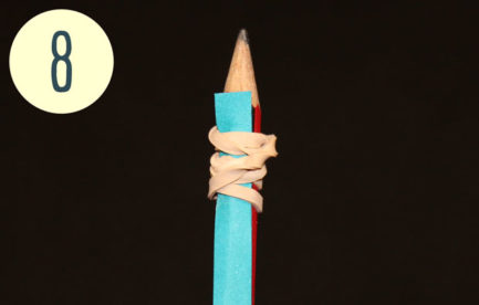 A paper strip is attache to the pointy end of a pencil.