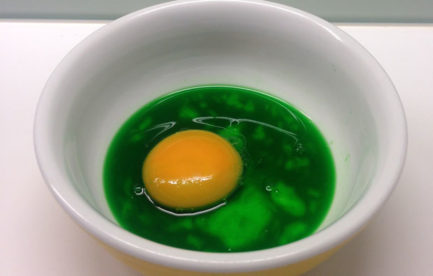 An egg with a green yolk in a bowl