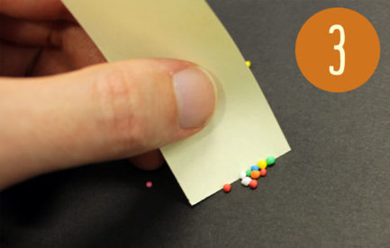 Someone separating 10 sprinkles with a piece of paper.
