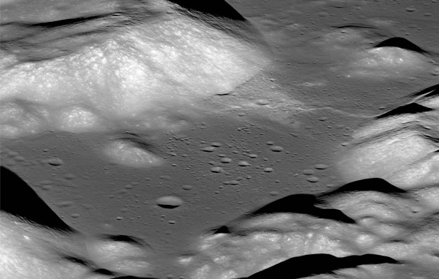 an image of the surface of the moon. There is a big, flat-bottomed valley. To the top, there is a thin wrinkle crossing the valley, and there are many small craters.