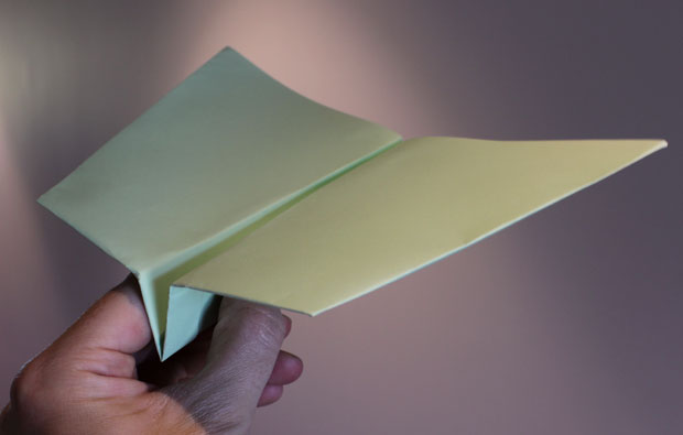 Hand holding a folded paper plane.