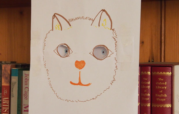 Drawing of a cat with cut out eyes.