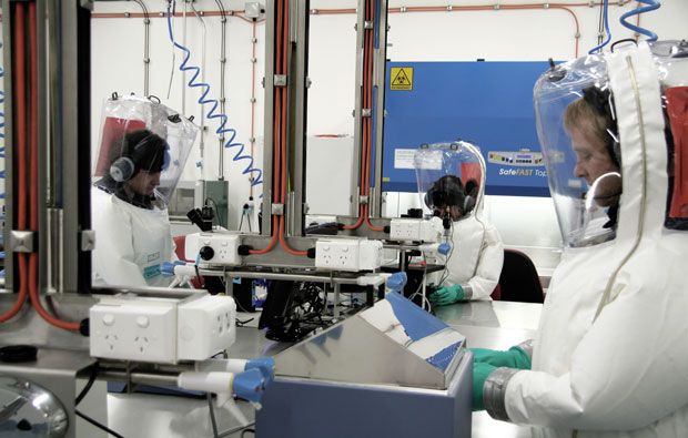Several scientists wearing protective suits in a lab
