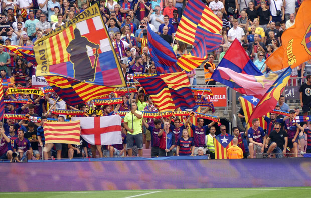 Crowd of football fans waving flags from the stands.