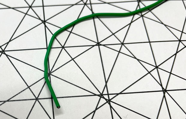 Green wire laying on a messy grid of lines