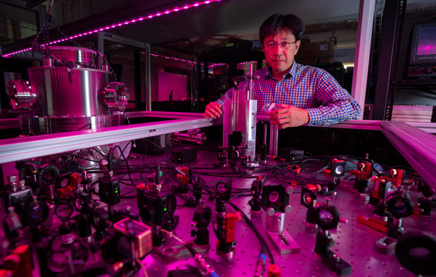 A scientist standing behind a complicated laser experiment