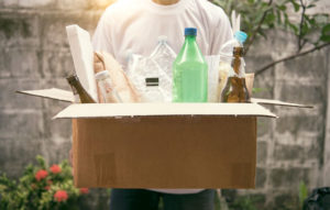 Person carrying a cardboard box full of recycling materials.