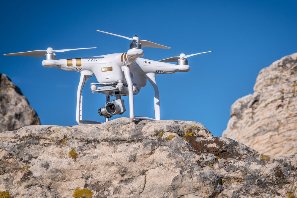 White drone landed on a rock.